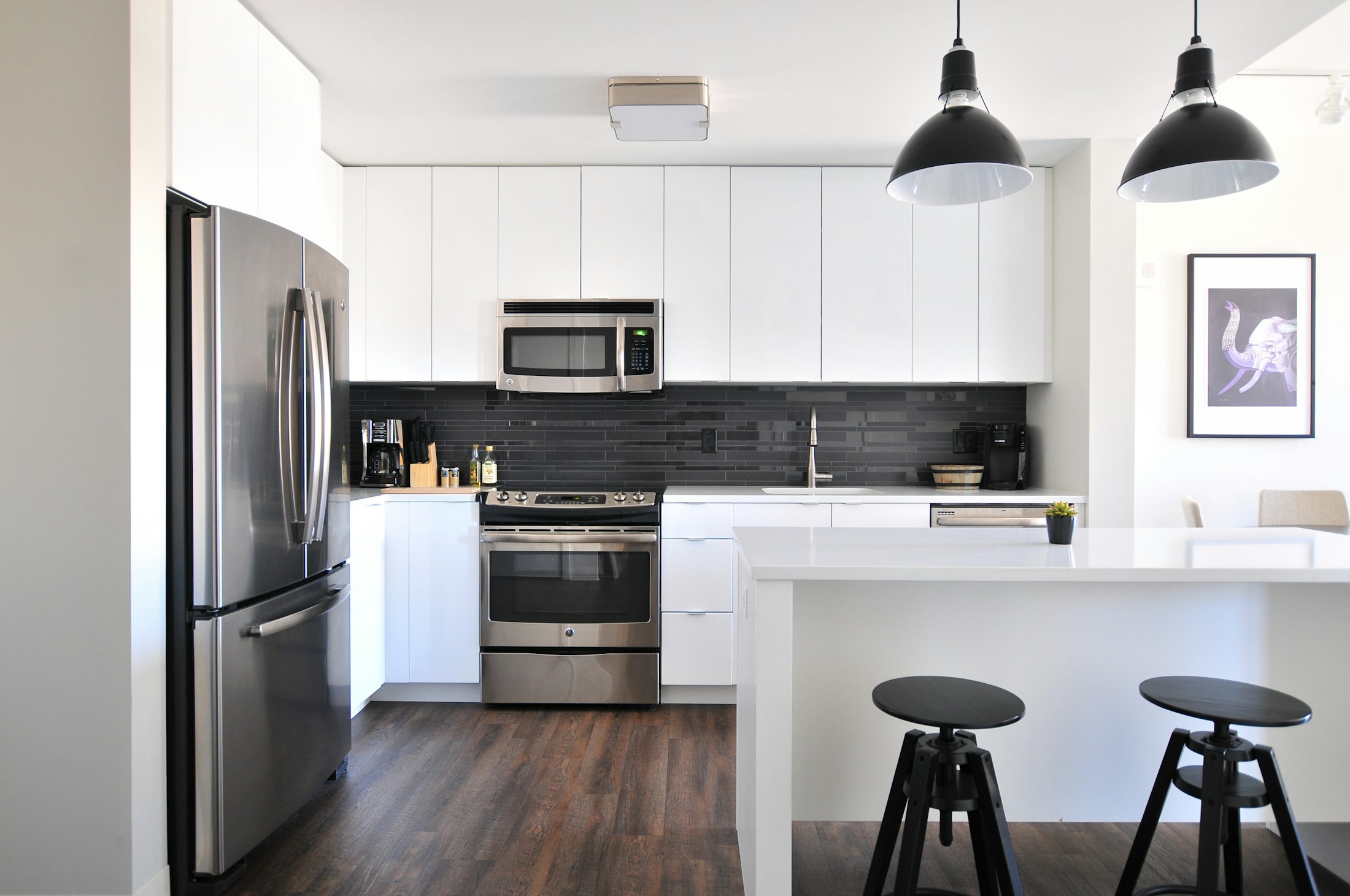 Gray steel refrigerator near a modular kitchen with modern appliances